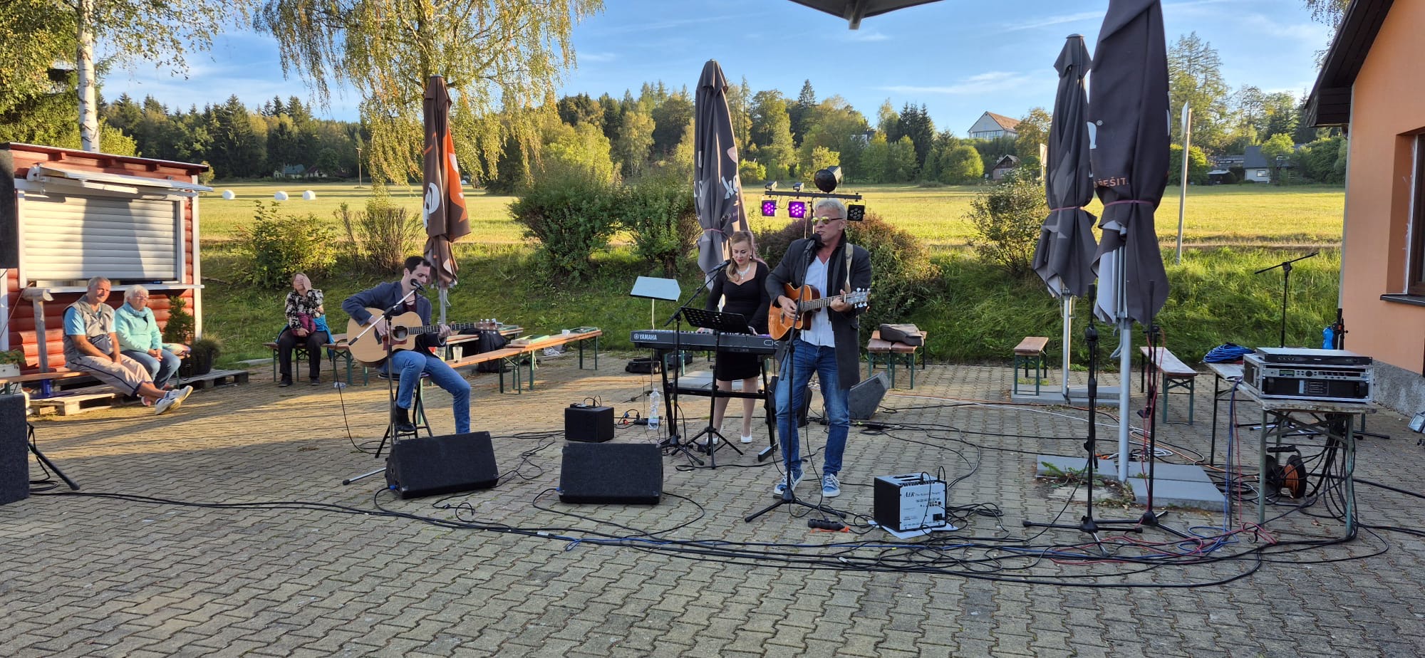 Trio s kytarami a klávesami na podvečerním pódiu