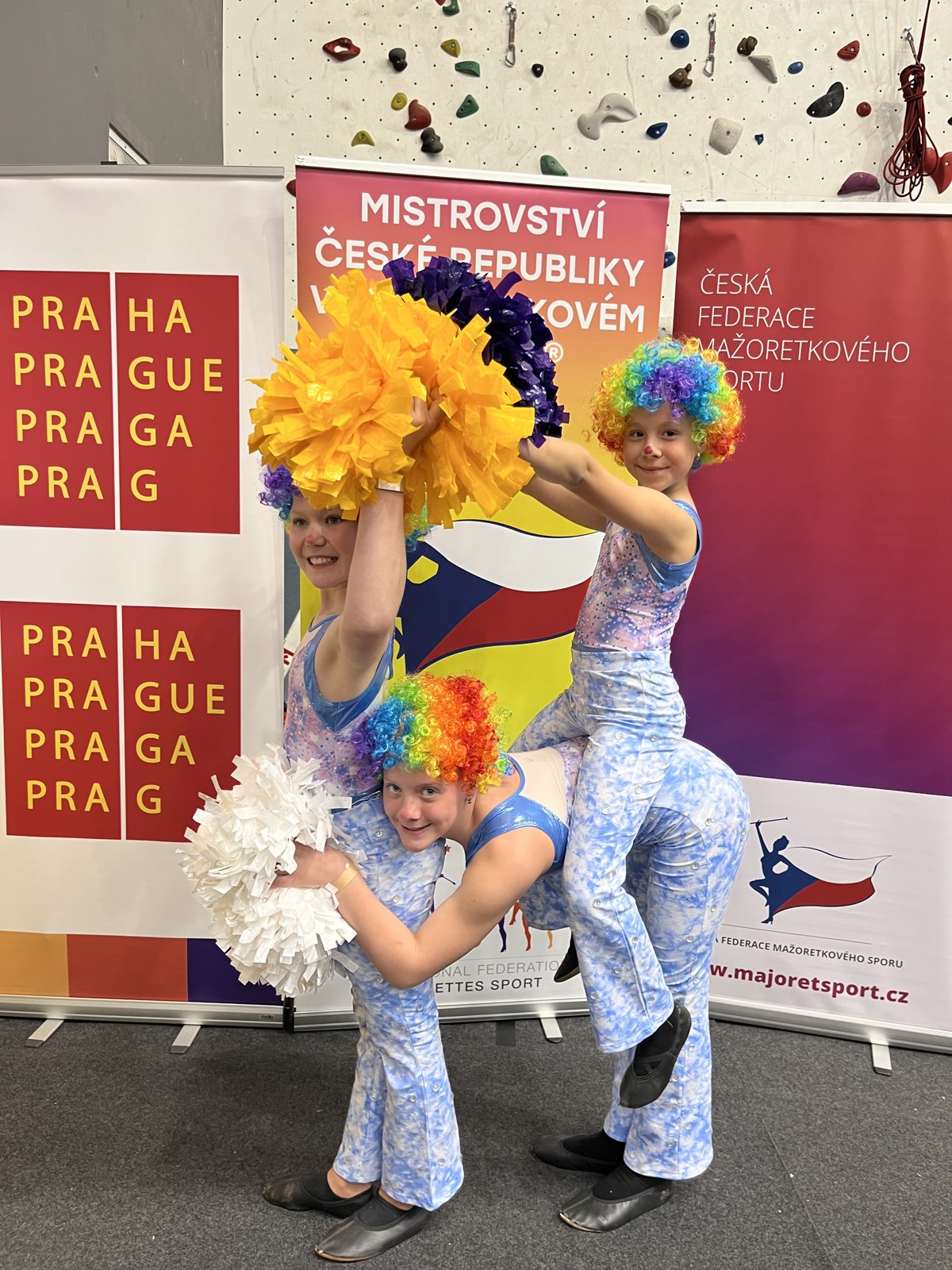 Mažoretky s pompony před soutěžní stěnou