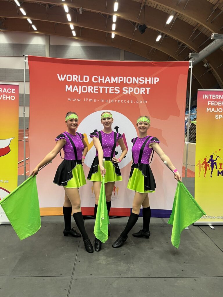 Trojice mažoretek s vlajkami na World Championship Majorettes Sport
